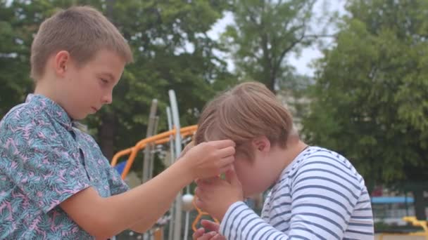 Ein Teenager hilft einem Jungen mit Down-Syndrom, eine Brille aufzusetzen. — Stockvideo