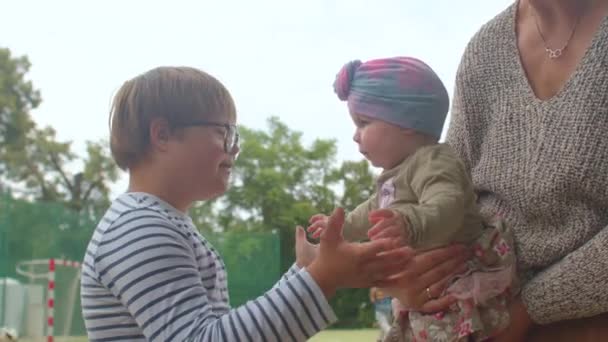 El niño con síndrome de Down se comunica con la niña pequeña. Él le dice su mensaje verbal. — Vídeos de Stock