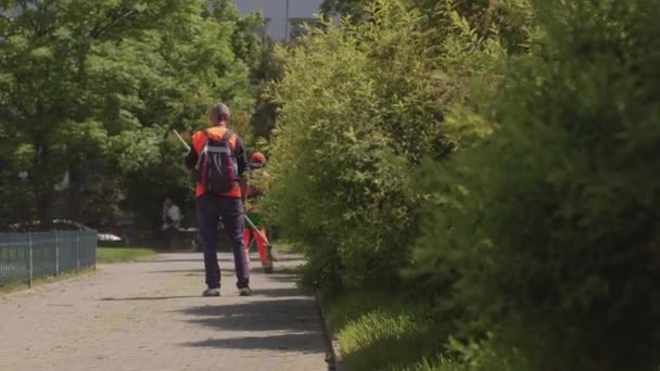 Street cleaner homme gilet orange avec les mains nettes prend des mesures le long du trottoir ville — Video