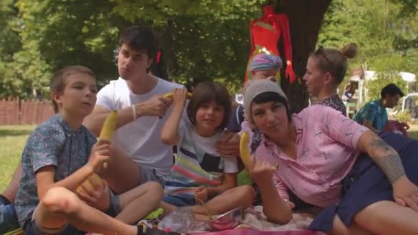 Grupo alegre de adultos jóvenes y niños posando con plátanos, tiroteo cómico — Vídeos de Stock