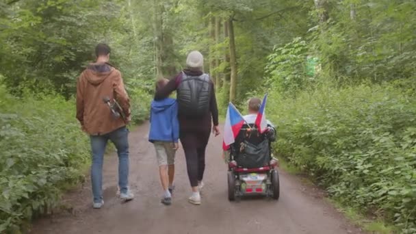 Family disabled person moves through forest park take steps carriage rolls — Stock Video