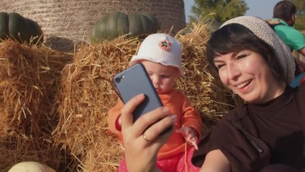 Baby in orangefarbenem Pullover und Panama. Mutter mit Tochter, Tätowierung, Sonnenbrille, Telefon. — Stockvideo