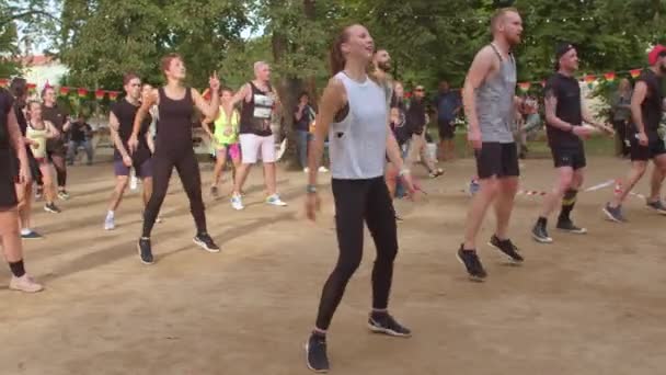 Aktywna kobieta sprawia, że taniec porusza tancerzy grupowych. Robią trening w parku miejskim. — Wideo stockowe