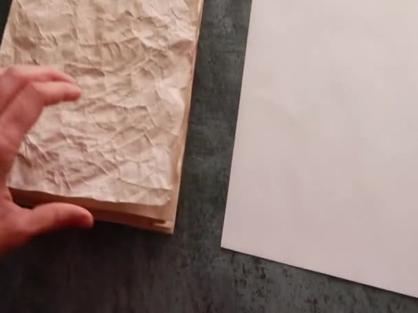 Hand vidrör en hög med gammalt papper som ligger på bordet bredvid tomma vita ark. — Stockvideo