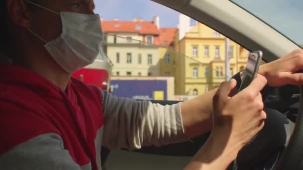 Masked driver mobil Dia menggunakan tangan telepon. Menggunakan aplikasi mobile — Stok Video