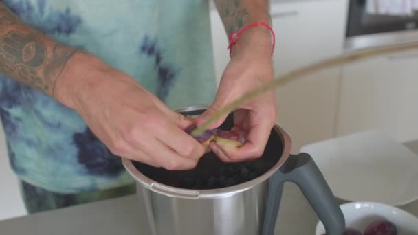 Il casse les prunes et les met dans la cuisine du mixeur. Préparation cocktail de vitamines — Video