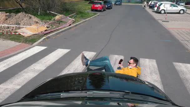 Yaya geçidinden düşen adam arabasının fotoğrafını çeken adama çarpıyor. — Stok video