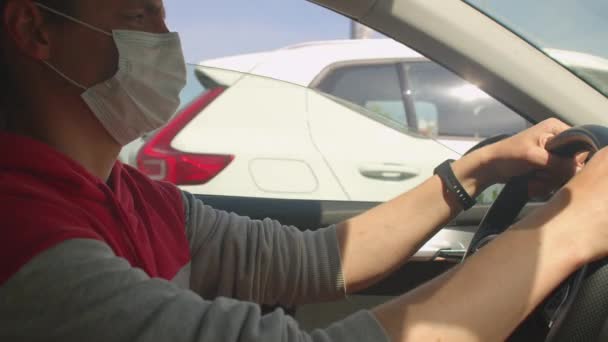 Ο οδηγός κρατά το τιμόνι με τα χέρια του. Μια μάσκα φοριέται στο πρόσωπό του. — Αρχείο Βίντεο