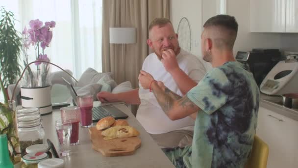 Gay hombre ofrece su amante bollos para el desayuno. El cuidado de la nutrición. Gente real. — Vídeos de Stock