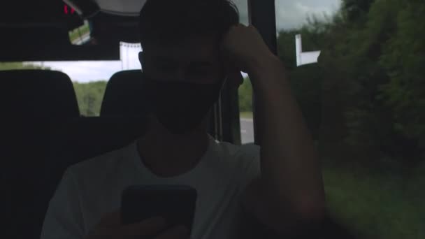 Мужчина разговаривает по телефону в автобусе общественного транспорта. На лице маска.. — стоковое видео