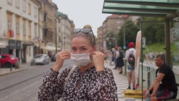 Menggunakan masker wajah di depan umum. Seorang wanita muda datang ke perhentian angkutan umum — Stok Video