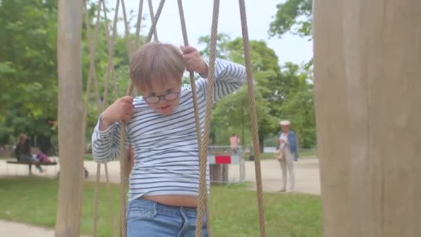 Rope coordination training. Down syndrome boy exercises body friend playground. — Stock Video