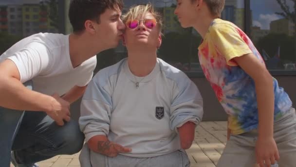 Een gehandicapte vrouw wordt gekust door een man en een kind. Belemmeringen in de samenleving — Stockvideo