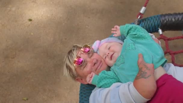 Kobieta niepełnosprawna na huśtawce z dzieckiem. Dzieci rodziców niepełnosprawnych. — Wideo stockowe