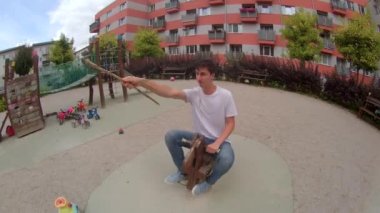 Çocuk parkındaki yetişkin adam. Tahta bir atın üzerinde oyuncak mızrağı olan bir binici. Açık hava.