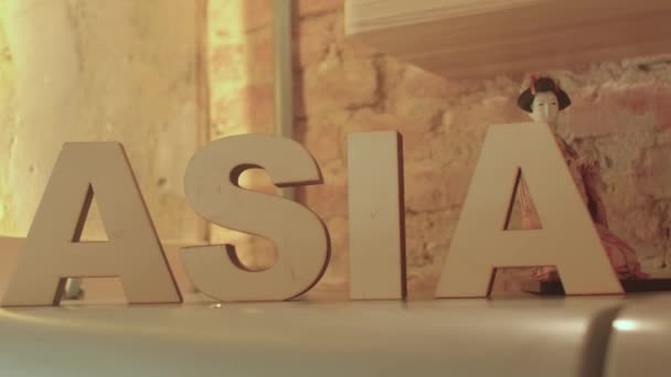 A palavra Ásia é feita de letras de madeira. Há um fundo de estatueta. — Vídeo de Stock