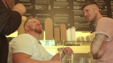 Restoranda garsonla konuşan iki adam. Sakalına eliyle dokunuyor..