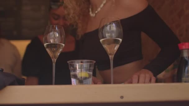 Le donne si siedono al tavolo del bar. C'è un bicchiere con un drink sul tavolo. — Video Stock