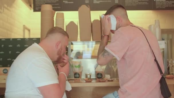 Two men go to bistro. He wipes off the sweat with a tissue on his forehead — Stock Video