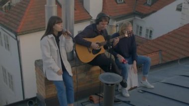 Açık hava müzik seansı. Gençler çatıda oynar ve şarkı söyler Eski bir Avrupa şehrinde.