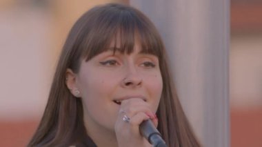 Mikrofona şarkı söyleyen bir kızın yakın çekimi. Kadın şarkıcı.. 