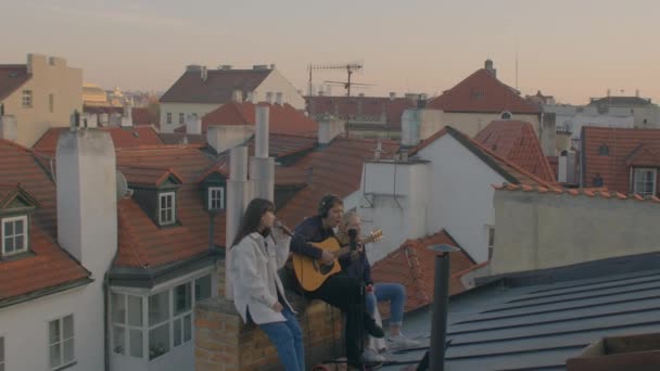 Молодые люди поют на крыше старого европейского города. Романтическое настроение, любовь — стоковое видео