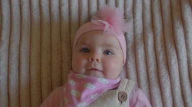 Kafasında pembe bir fiyonk olan küçük bir kızın yakın plan portresi.