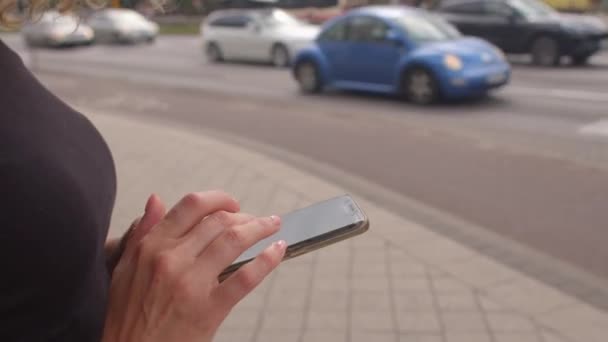 Женские руки нажимают на экран смартфона возле автодороги. — стоковое видео