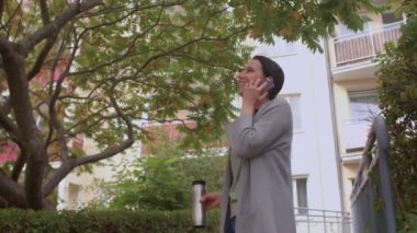 Kadın evin yakınındaki ağacın altında telefon kullanıyor. Arkadaşını arayıp tartışıyor.