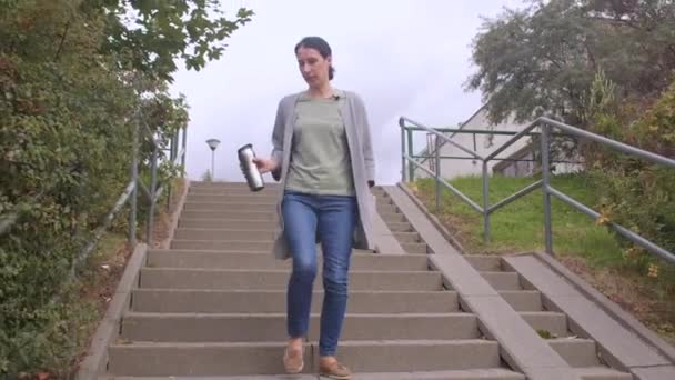 Kobieta z farbą termiczną w rękach schodzi po schodach miasta.. — Wideo stockowe