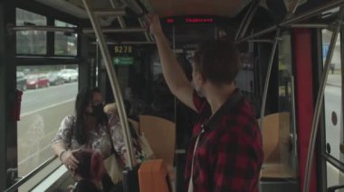 Maskeli adam toplu taşıma tramvayında tırabzan tutuyor. Solunum koruması COVID-19.