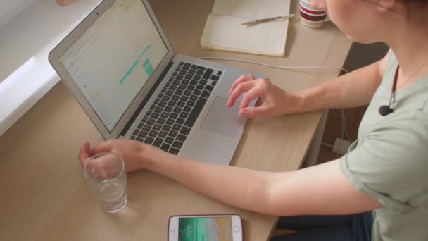 Mujer freelancer utiliza mesa portátil. Presiona el teclado, se desplaza en el monitor. — Vídeo de stock