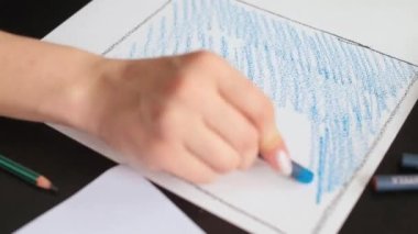 Kadın el boyası kağıdı maviye boyuyor. Psikoterapi gören hastaları çiziyor.