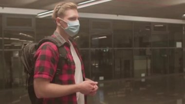 Yüzünde maske olan genç adam karantina önlemleri hakkında yorum yapıyor..