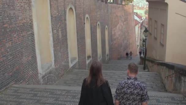 Сзади пара движется вниз по лестнице в городе Они перемещаются по городу. — стоковое видео