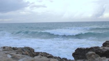 Fırtınalı havada deniz dalgalı. Dalgalar kayalara çarpar.