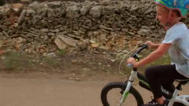 Kasklı çocuk yolda bisiklete biniyor. Yüksek hız heyecanı tetikler. — Stok video