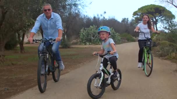 A família monta bicicletas na estrada no lazer ativo da floresta — Vídeo de Stock