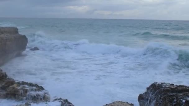 La ola de energía del agua golpea la montaña de la costa rocosa. El agua salada vuela. — Vídeos de Stock