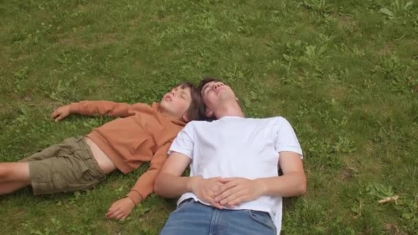 Enfant au repos et professeur. Dormir en plein air pendant la journée et se détendre sur l'herbe. — Video