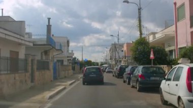 Pulia 'da seyahat ediyor. Sağda park yeri olan şehir yolu. Palmiye ağaçları.