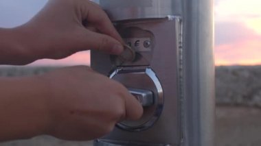 El, mekanik dürbün otomatına 1 Euro atıyor. Seyahat işi.