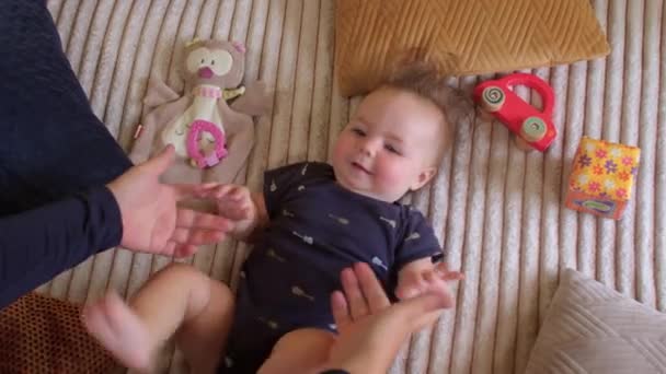 Baby stijgt naar zittende positie houdt de handen van een ouder. Baby ontwikkeling. — Stockvideo