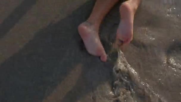 Nohy malého chlapce se plazí po pláži na břehu přehrady. — Stock video