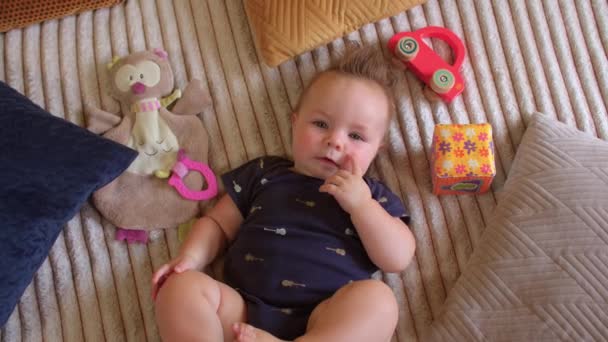 Retrato de bebé recién nacido en azul. Niño sonríe y sostiene un dedo en su boca. — Vídeo de stock