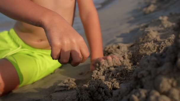 Крупный план руки ребенка строит башню из песка на пляже. — стоковое видео