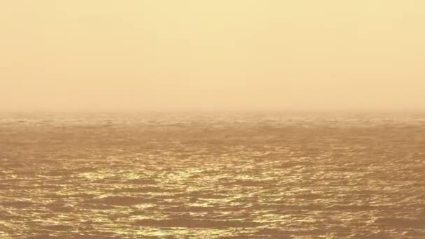 Dalgalar deniz suyu, güneşin sarı ışığıyla aydınlatılır.. — Stok video