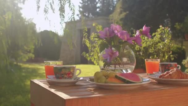 Breakfast on table. Flowers are in vase, croissant is on plate, in cups coffee. — Stockvideo