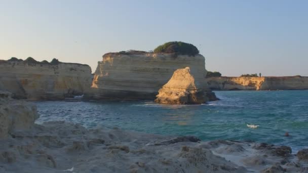 Rocky stone coast sea. Waves hitting stones sun illuminates stone in distance — ストック動画