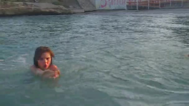 Radostné děti plavou ve vodě moře. Cákají, skákají. — Stock video
